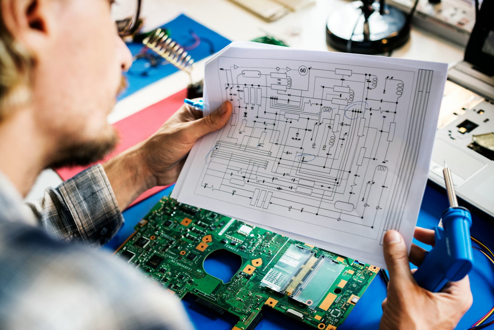 Engineer reviewing a schematic beside a populated board