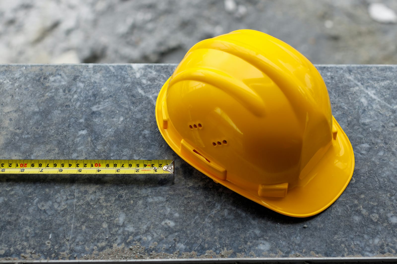 Safety helmet and measuring tape resting on quarried stone