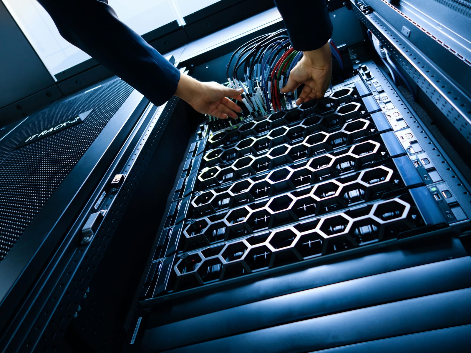 Hands connecting patch cables into a server rack